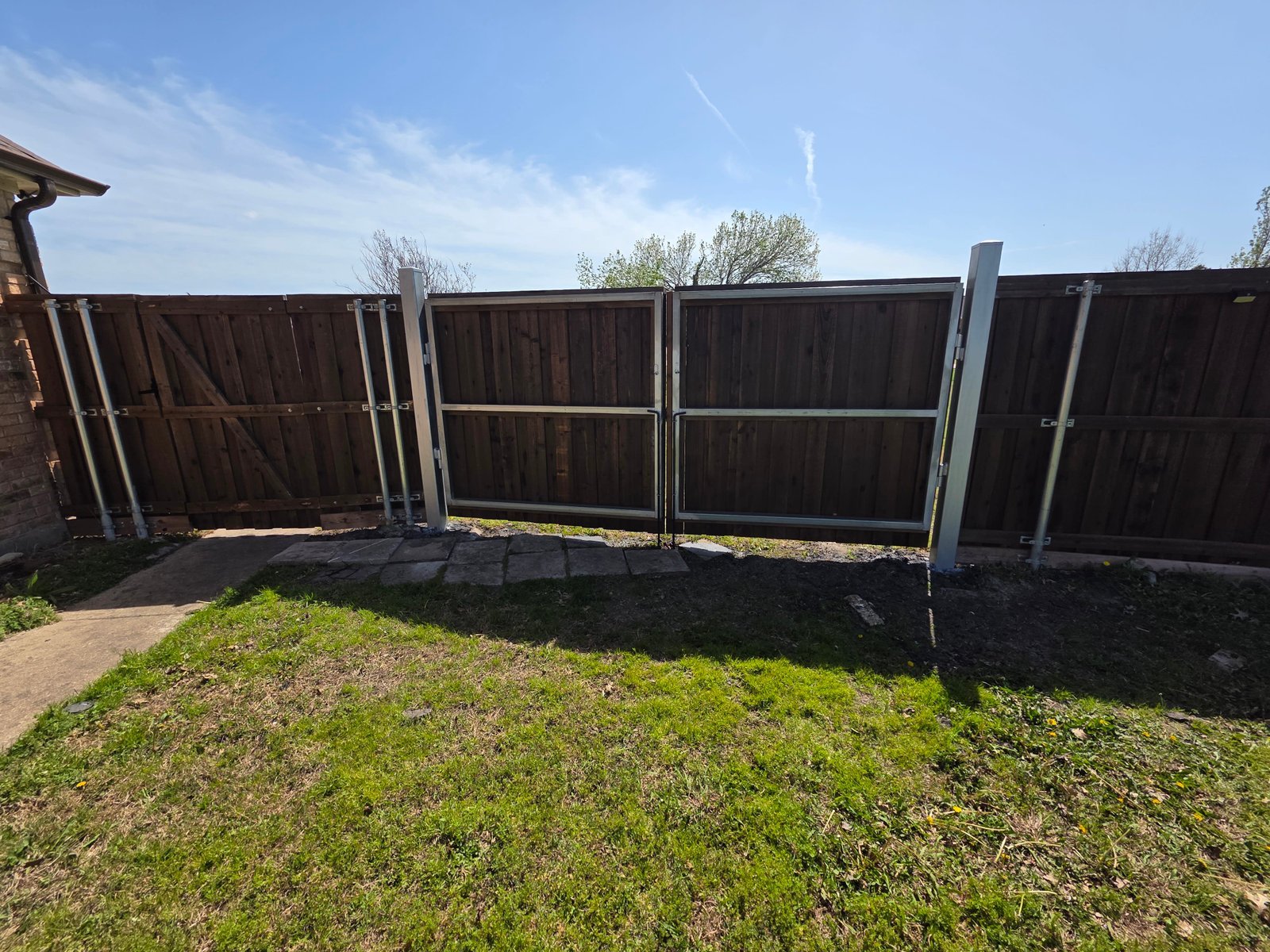 Metal double swing gate across a paved driveway