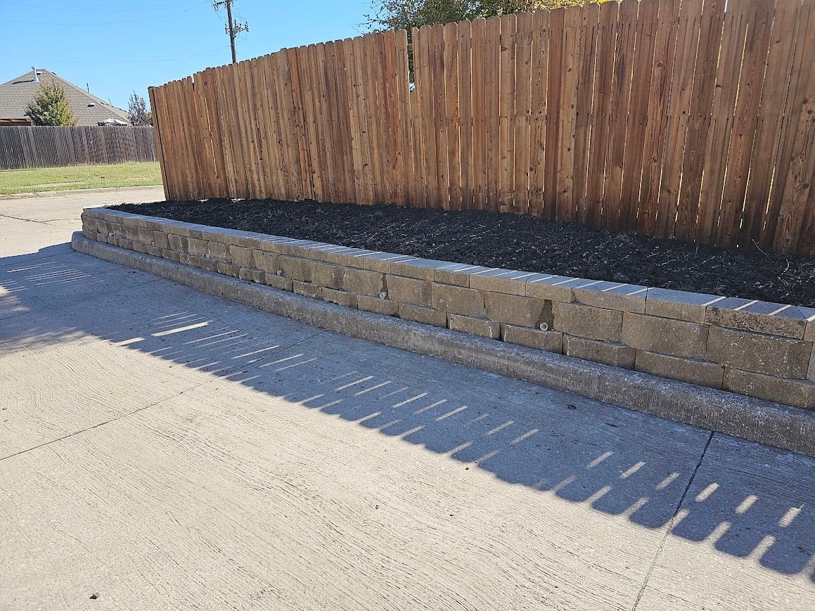 Textured stone block retaining wall along a tiered garden